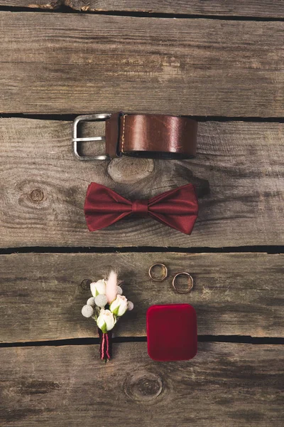 Pose plate avec des accessoires de marié arrangés et des alliances sur le dessus de table en bois — Photo de stock