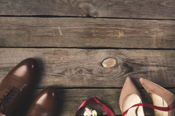 Flache Lage mit Schleife, Corsage, Braut- und Bräutigamsschuhen auf hölzerner Tischplatte — Stockfoto