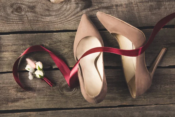 Top view of beautiful bridal shoes and corsage on wooden tabletop — Stock Photo
