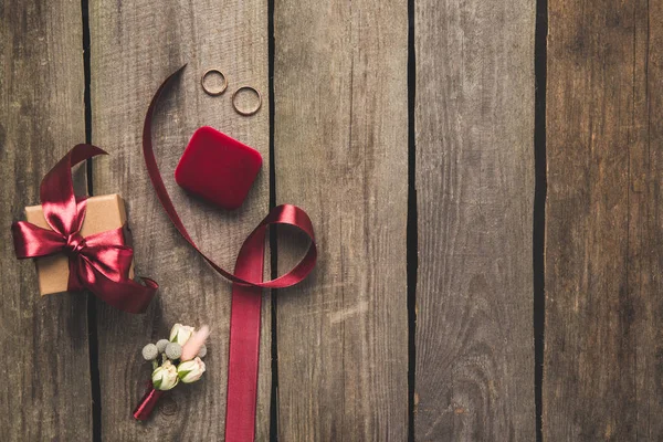 Leigos planos com fita, anéis de casamento, corpete e presente na mesa de madeira — Fotografia de Stock