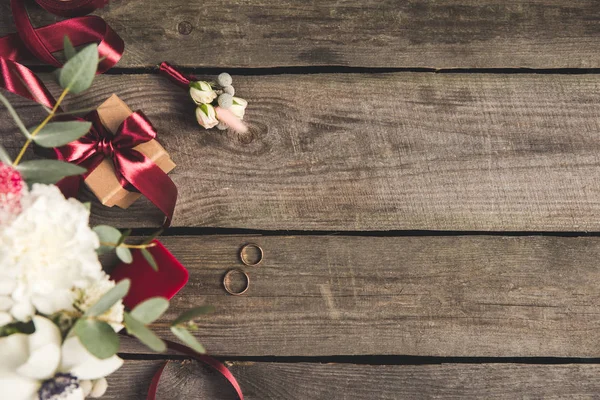 Plano con anillos de boda, joyero, ramo de novia y ramillete en la mesa de madera - foto de stock