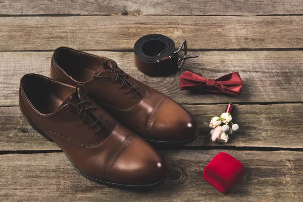 Vista de perto dos noivos dispostos sapatos e acessórios na superfície de madeira — Fotografia de Stock