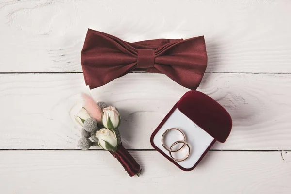 Flat lay with buttonhole, bow tie and jewelry box on wooden surface — Stock Photo