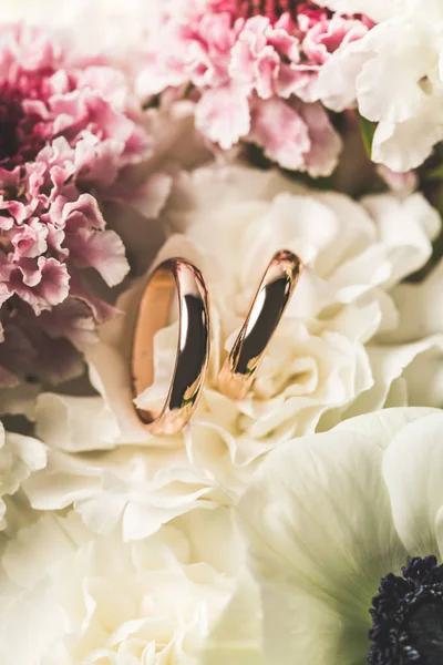 Vista de cerca de los anillos de boda en ramo de novia - foto de stock