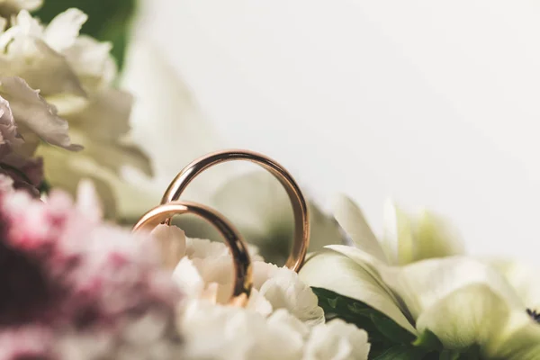 Vista de cerca de los anillos de boda en ramo de novia - foto de stock