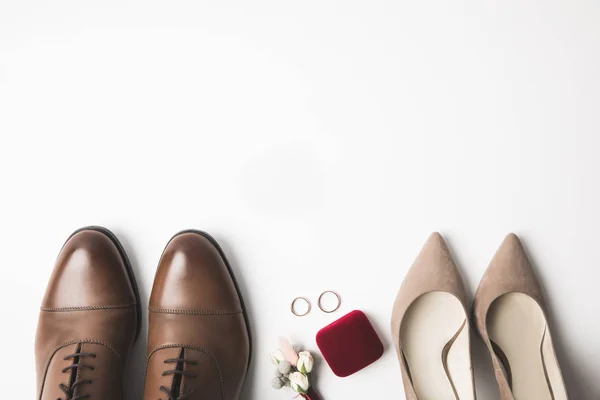 Vista superior de pares de zapatos de novia y novio, ramillete, joyero y anillos de boda aislados en blanco - foto de stock