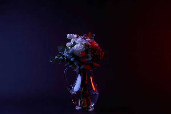 Bouquet of white flowers in glass vase on dark — Stock Photo