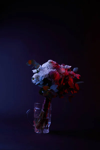 Ramo de flores diferentes en vaso de cerveza en la oscuridad - foto de stock