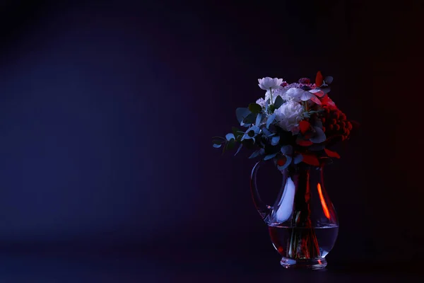 Bouquet de différentes fleurs en carafe avec de l'eau sur fond sombre — Photo de stock