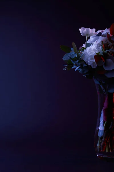 Buquê de flores diferentes em vaso de vidro no escuro — Fotografia de Stock