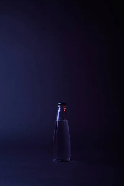 Закрита пляшка води на темній поверхні — стокове фото