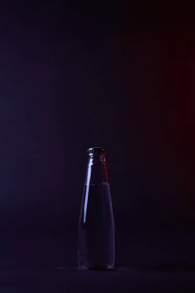 Botella cerrada de agua en la superficie oscura - foto de stock