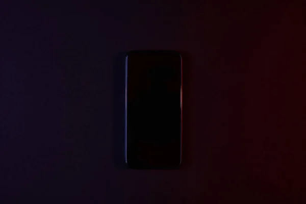 Top view of black smartphone on dark — Stock Photo