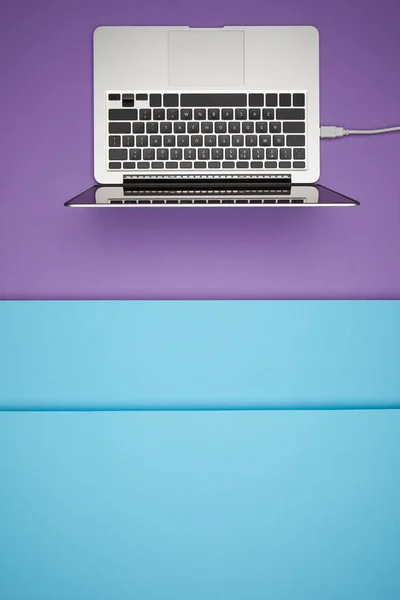 Top view of laptop on purple and blue paper background — Stock Photo