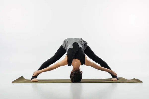 Mujer practicando yoga y haciendo doblez de piernas anchas hacia adelante - foto de stock