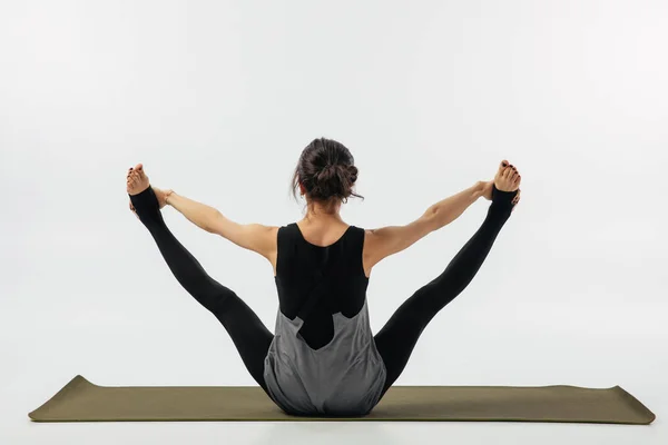 Vista trasera de la mujer practicando yoga asana urdhva upavistha konasana aislada sobre blanco - foto de stock