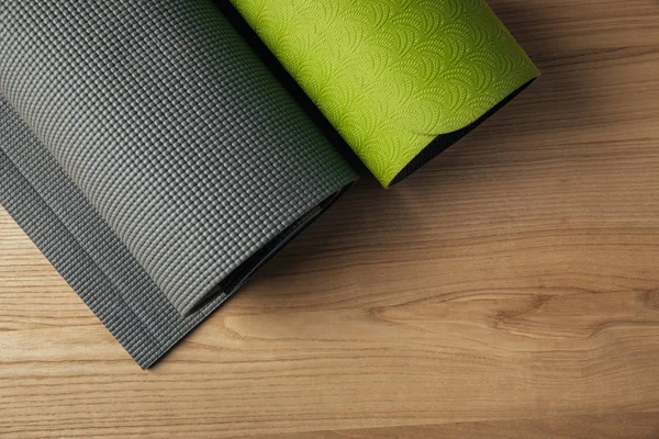 Vista superior de dois tapetes de ioga verde e cinza no chão de madeira — Fotografia de Stock
