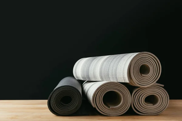 Verschiedene gerollte Yogamatten auf Holztisch — Stockfoto