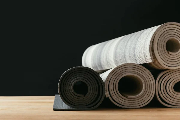 Diferentes esteras de yoga enrolladas en la mesa de madera - foto de stock