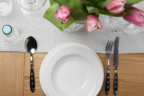 Geschirr mit Tellern auf dem Tisch mit Blumen in der Vase — Stockfoto