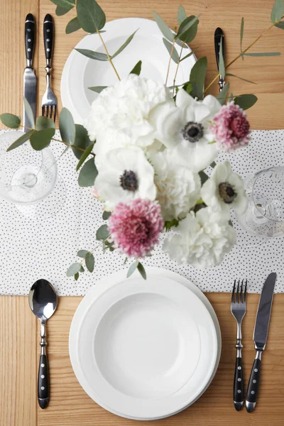 Mesa festiva con cubiertos y platos sobre mesa con flores - foto de stock