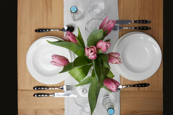 Dinnerware with plates on table with flowers in vase — Stock Photo