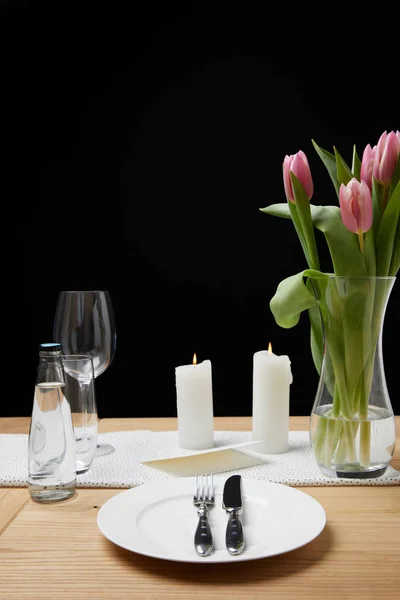 Vaso con mazzo di fiori e candele su tavola con stoviglie festive — Foto stock