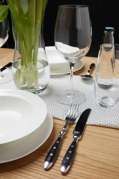 Vaisselle avec verres sur la table à côté du bouquet dans le vase — Photo de stock