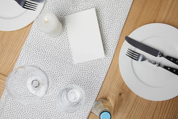 Mesa festiva con cubiertos en platos sobre mesa con tarjeta en blanco - foto de stock