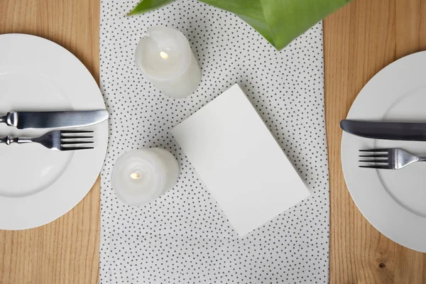 Jantar com talheres na mesa ao lado de cartão em branco e velas — Fotografia de Stock