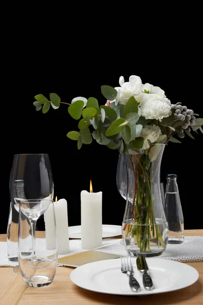 Tavolo festivo con posate su piatti su tavolo con candele su sfondo nero — Foto stock