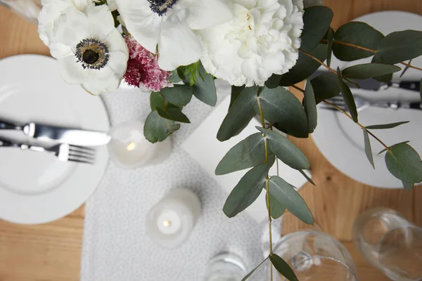 Обстановка столу з столовими приборами на тарілках на столі з квітами — стокове фото