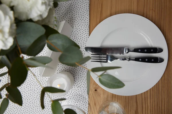 Tischdekoration mit Besteck auf Teller auf Tisch mit Blumen — Stockfoto