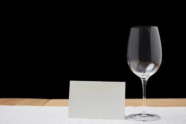 Verre à vin vide et carte blanche sur table sur fond noir — Photo de stock