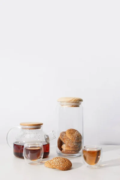 Nahaufnahme von Tee in Tassen, leckeren Keksen und Teekanne auf grau — Stockfoto
