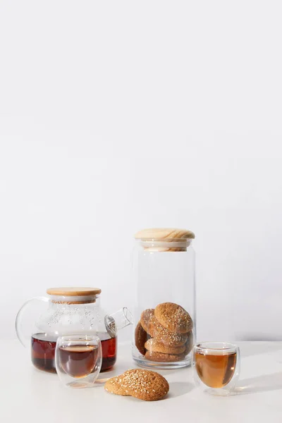 Vista de cerca del té en tazas, deliciosas galletas y tetera en gris - foto de stock