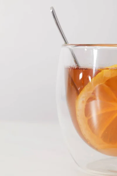 Xícara de vidro com chá quente fresco, colher e fatia de limão em cinza — Fotografia de Stock