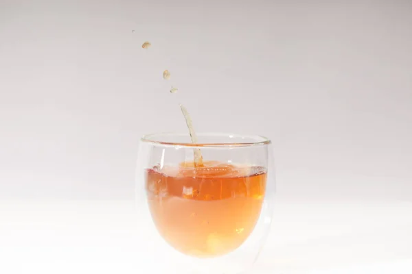 Vista ravvicinata di versare il tè caldo fresco in tazza di vetro sul grigio — Foto stock