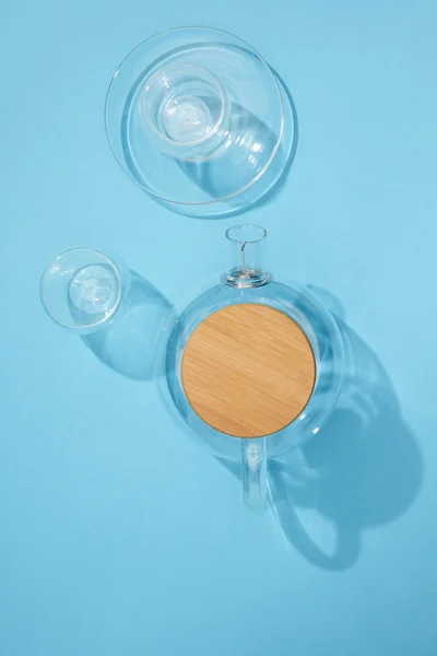 Vue du dessus de théière en verre vide avec tasse, assiette et bol sur bleu — Photo de stock
