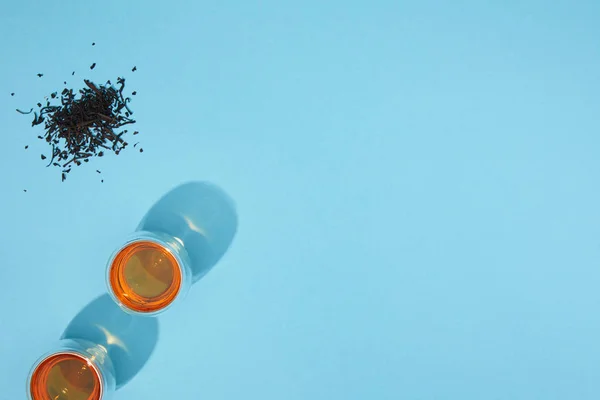 Top view of glasses with fresh hot tea and dry herbal tea on blue — Stock Photo