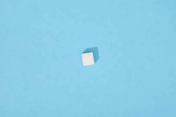 Dulce cubo de azúcar blanco con sombra sobre azul - foto de stock