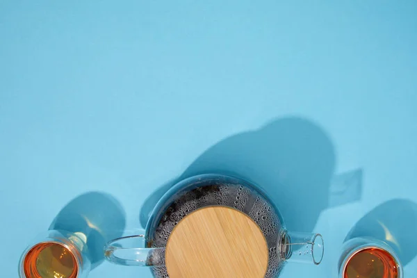 Vista superior de la tetera y tazas de té caliente fresco en azul - foto de stock