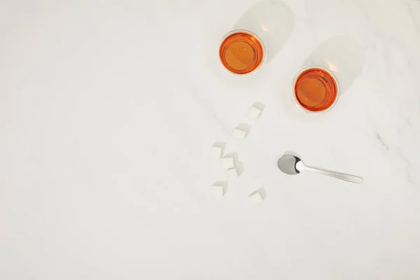 Top view of fresh hot tea in glass, sugar cubes and spoon on grey — Stock Photo