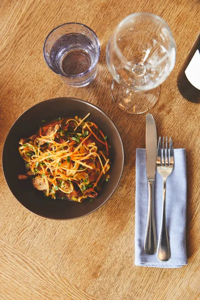 Cena con fideos udon y cerdo con cubiertos en la mesa - foto de stock