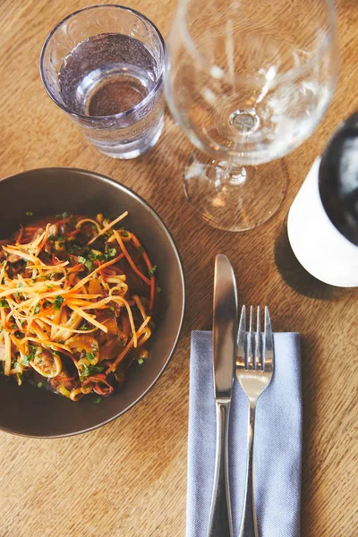 Top view of udon noodles and pork with cutlery on table — Stock Photo