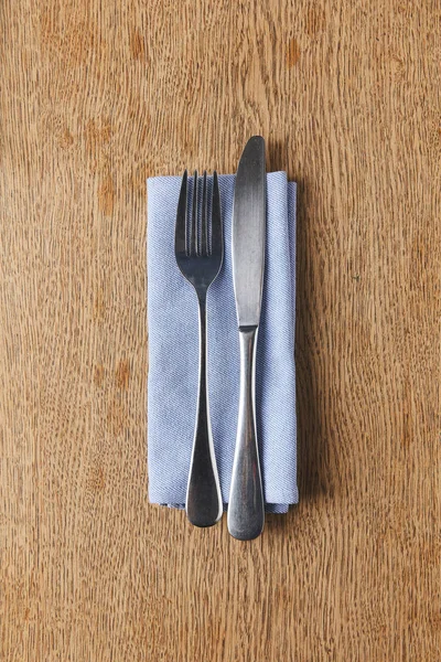 Tenedor y cuchillo en servilleta sobre mesa de madera - foto de stock