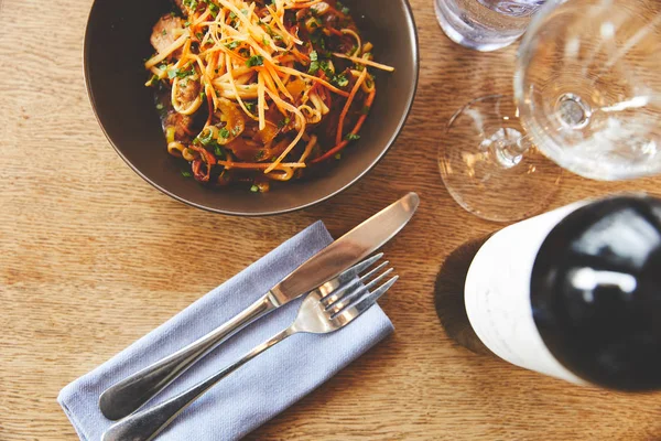 Cena con fideos udon y cerdo con cubiertos en la mesa - foto de stock