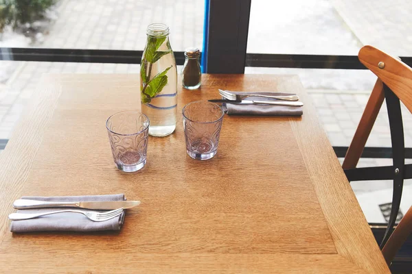 Bottle with mint water and glasses on table — Stock Photo