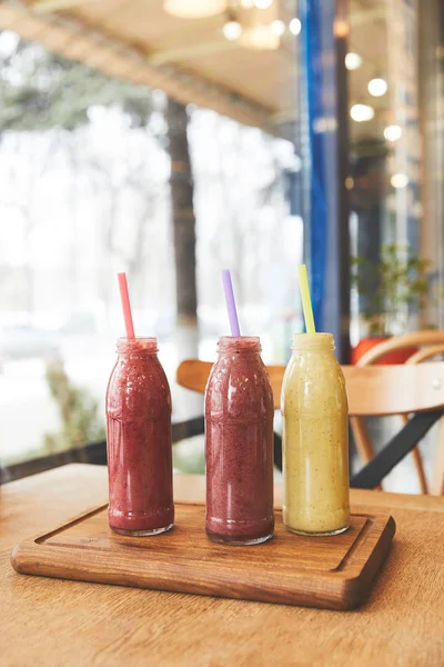 Bottles with assorted smoothies on wooden table — Stock Photo