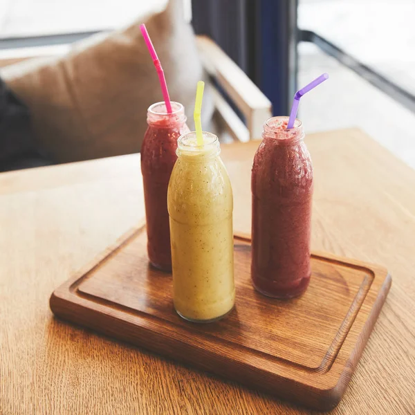 Flaschen mit Smoothies aus frischen Früchten und Beeren auf dem Tisch — Stockfoto